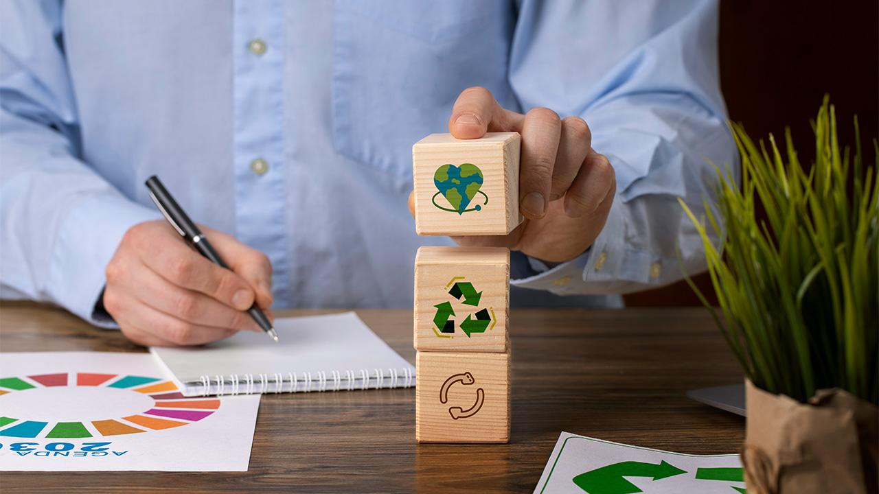 Homem montando blocos com símbolos de sustentabilidade em referência ao ESG em 2023.