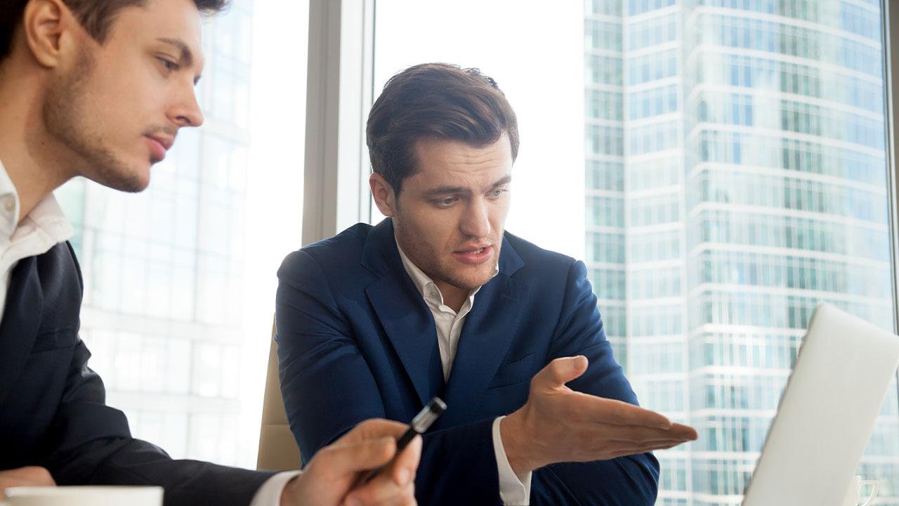 Auxiliar de contabilidade explicando resultados a gestor.