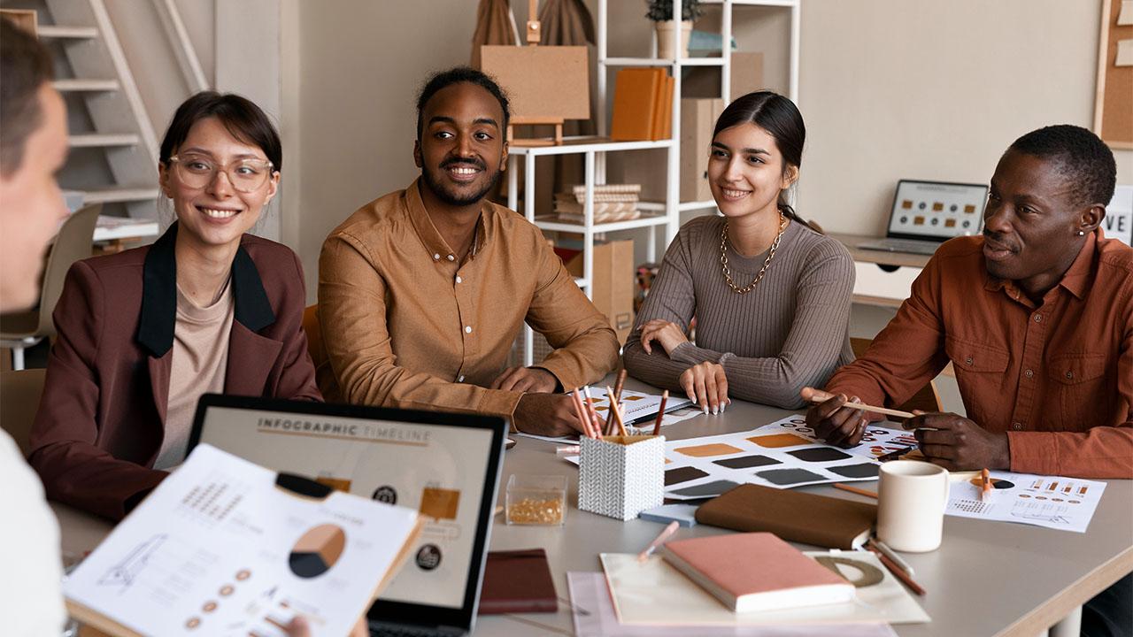 Uma equipe com quatro empresários diversos, duas mulheres e dois homens negros, em referência ao tema diversidade e inclusão.