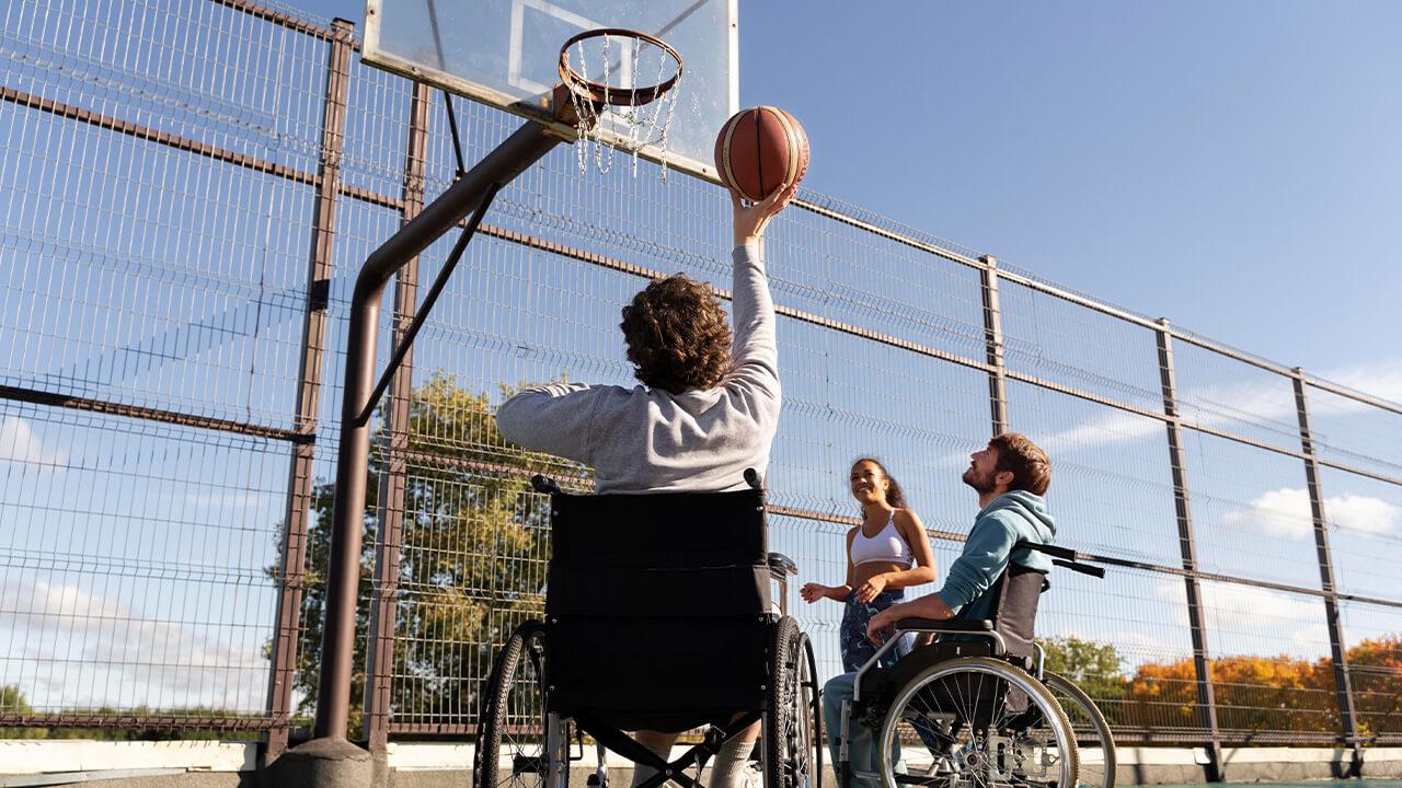 Crianças em cadeira de rodas brincam de basquete junto a outras crianças.