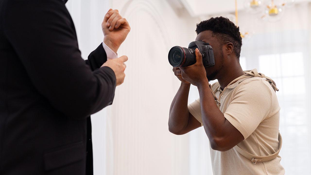 Fotógrafo praticando habilidades de fotografia enquanto fotografa um homem.