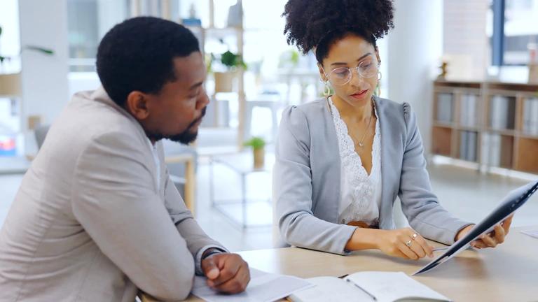Uma líder de equipe transmite feedback a um funcionário em sala de reuniões. Conceito: como fazer um feedback construtivo.